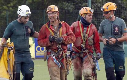 Two of the four cavers are accompanied by their rescuers.