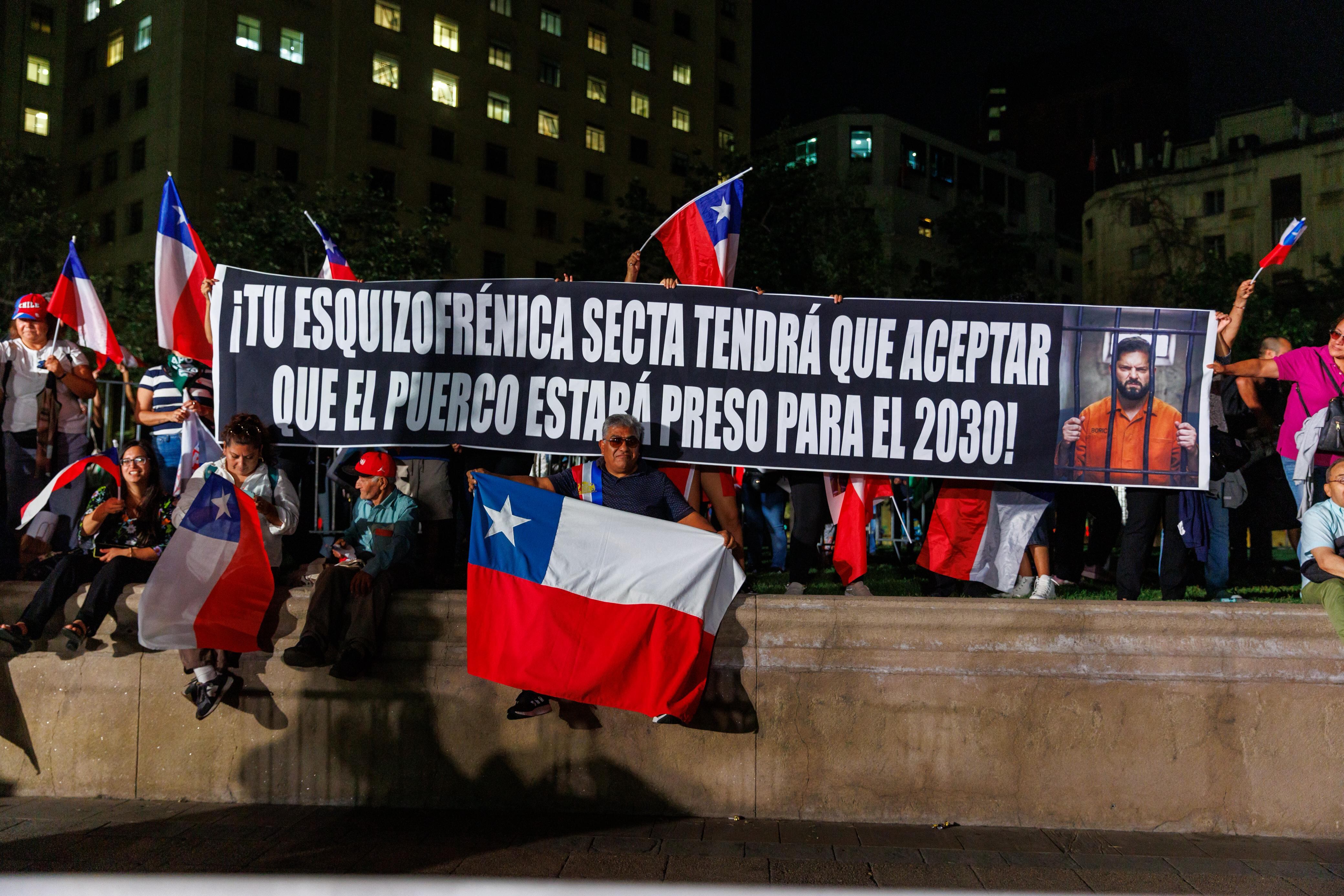 Personas sostienen una pancarta con una imagen que muestra al expresidente Gabriel Boric en la cárcel durante el discurso del presidente de Chile José Antonio Kast, en Santiago de Chile, el 11 de marzo de 2026.