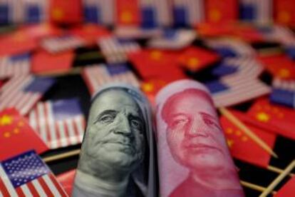 Billetes de dólar y yuan entre banderas de EE UU y China.
