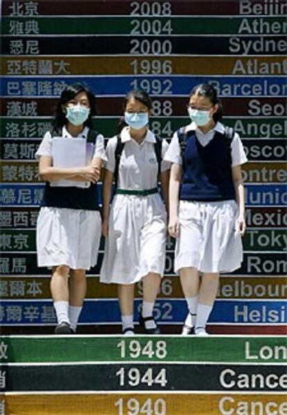 Dos estudiantes de pasean con una mascarilla.