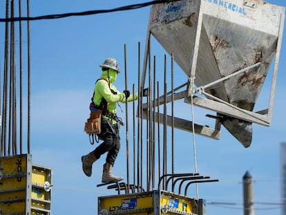 A worker guides a bin into position at a construction site, Tuesday, Jan. 24, 2023, in Miami.
