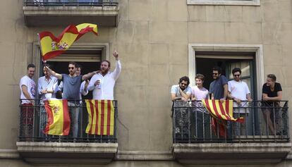 Varias personas saludan desde dos balcones a los participantes de la manifestación de Barcelona.