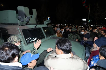 Ciudadanos rodean un vehículo militar en el exterior de la Asamblea Nacional, en Seúl el martes.