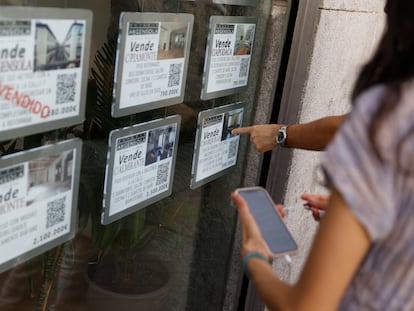 Unas personas se paran delante del escaparate de una inmobiliaria que publicita los inmuebles que gestiona, este lunes en el centro de Madrid.