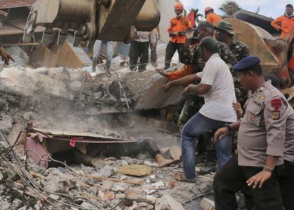 Personal de rescate recuperan el cadáver de una persona entre los escombros de un edificio en la ciudad de Pidie Jaya (Indonesia).