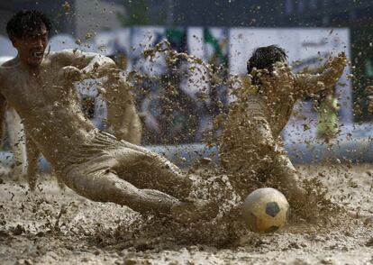 Los jugadores luchan por el balón durante un torneo de fútbol en el barro en Pekín (China).