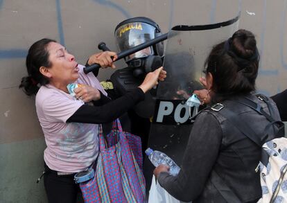 Una mujer lucha con un agente antidisturbios durante una protesta que exige la disolución del Congreso y celebrar elecciones democráticas en lugar de reconocer a Dina Boluarte como presidenta de Perú, este lunes en Lima.