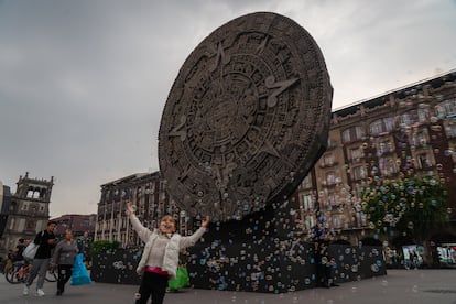 Una niña juega frente una escultura que representa a la Piedra del Sol mexica. 