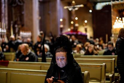 Una mujer vestida de 'manola' mira su teléfono móvil antes de iniciarse la procesión de Los Estudiantes en Madrid, el 25 de marzo.