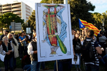 Un manifestante sujeta una carta gigante que representa al rey de bastos boca abajo, durante la protesta independentista contra la visita de la familia real a Barcelona.