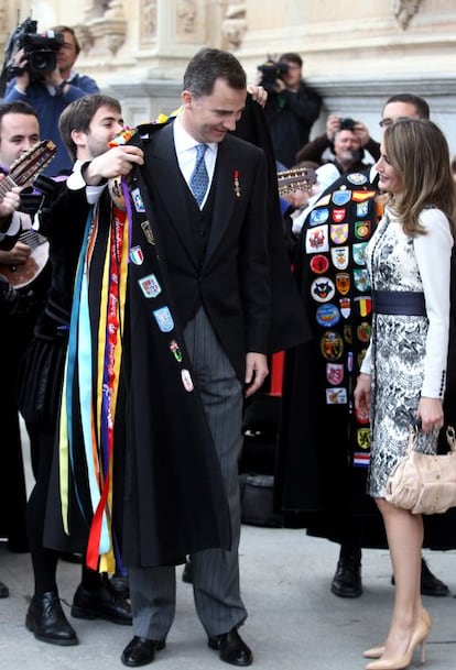 Un miembro de la Tuna universitaria de Alcalá le coloca la capa al Príncipe Felipe al final de la ceremonia.