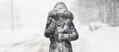 Una mujer se cubre del frío y la nieve en Reino Unido. 