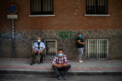 Tres vecinos esperan su turno ante la puerta del centro de salud Puerta Bonita, en Carabanchel, Madrid.