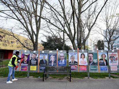 Una persona pega carteles electorales de los candidatos a las presidenciales francesas, en Saint-Herblain, el pasado  28 de marzo.