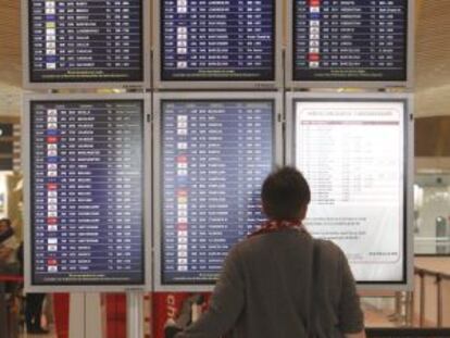 Un hombre mira los paneles de información de vuelos en el aeropuerto de Barajas en Madrid.