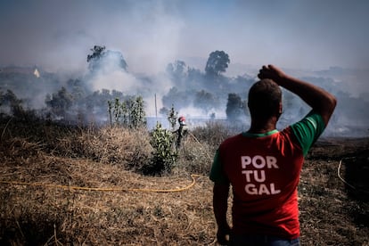 Hasta la tarde del domingo estaban activos 107 incendios, que se concentraban en los distritos de Oporto (34), Lisboa (13) y Braga (8), y que han causado una quincena de heridos. De forma preventiva se evacuaron varias aldeas. En la foto, un hombre observa el fuego forestal que amenaza las viviendas en Caneças, Lisboa, este domingo.   