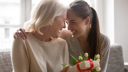 Una madre y una hija sonrientes con un regalo.
