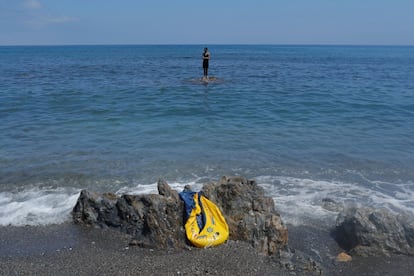 Un joven permanece subido a una roca frente a la playa del Tarajal, en la frontera de Ceuta. La llegada de personas a nado y a pie ha sido constante durante todo el lunes y continúa en la mañana de este martes en la misma playa donde se han desplegado tanques.
