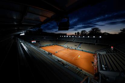 Panorámica de la pista Simonne Mathieu de Roland Garros, con luces artificiales, durante un partido al anochecer entre Khachanov y Majchrzak.