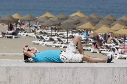 Un turista descansa al sol en la playa de La Malagueta de Málaga.