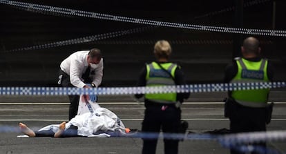 Un policía junto a un fallecido tras el ataque.