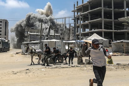 Un hombre corre a ponerse a cubierto tras un bombardeo israelí contra un edificio este viernes en Ciudad de Gaza.