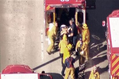 Los bomberos introducen a un herido en una ambulancia en el exterior del aeropuerto de Los Ángeles.