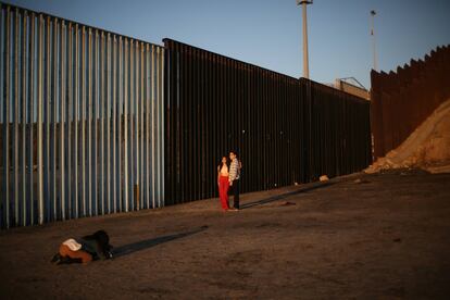 Unos turistas se hacen una fotografía al lado de la valla que sirve de frontera entre México y Estados Unidos, en Tijuana (México).