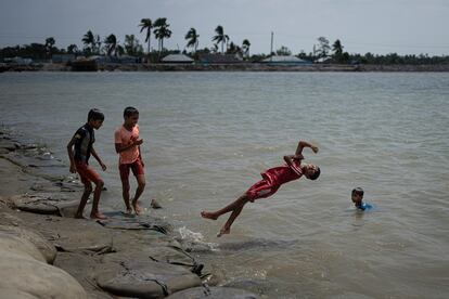 Un grupo de niños juega en el agua donde antes había tierra. Saltan desde el terraplén construido por los habitantes para proteger Pratapnagar de la erosión. Este municipio es uno de los más afectados por los ciclones y fue el más castigado de todo Bangladés por el ciclón Aila, en 2009.