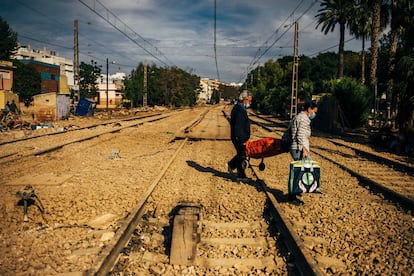 Dos vecinos de Alfafar cruzan las vías del tren con un carrito, este martes.