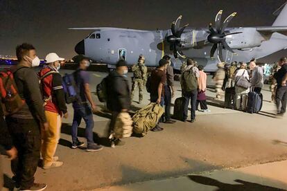 Ciudadanos franceses y sus colegas afganos hacen cola para embarcar en el avión militar que los va a evacuar de Afganistán en el aeropuerto de Kabul, este martes.