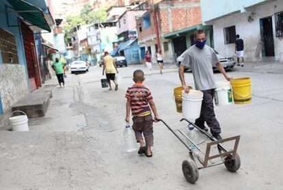 Vecinos de Petare, un barrio de Caracas, transportan agua durante la pandemia.