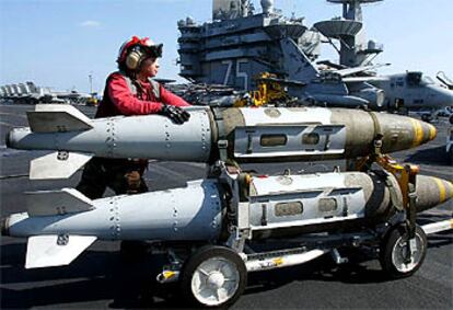 Una soldado estadounidense traslada dos bombas a bordo del portaaviones <i>Harry Truman.</i>