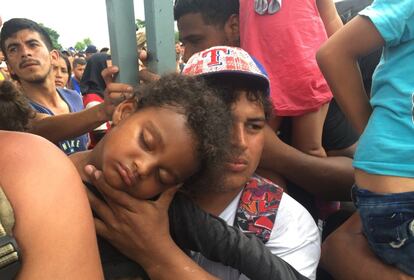 Pegado a la cerca, un padre llora con su hija en brazos. La niña se ha desmayado por la falta de agua y las horas de calor.