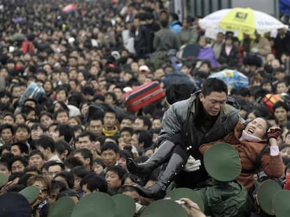 Los policías tratan de evacuar a una mujer enferma de entre la multitud que intenta entrar a la estación de tren de la ciudad de Guangzhou.