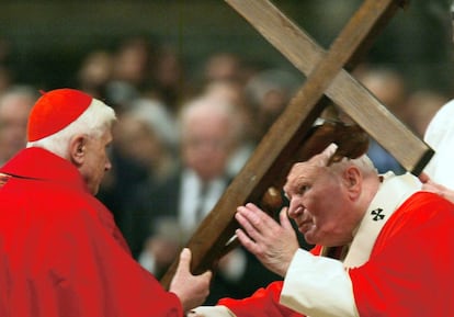 El papa Juan Pablo II coge la cruz que le ofrece el cardenal Joseph Ratzinger en la celebración del Viernes Santo en la basílica de San Pedro del Vaticano, el 9 de abril de 2004.