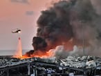 EDITORS NOTE: Graphic content / A helicopter puts out a fire at the scene of an explosion at the port of Lebanon's capital Beirut on August 4, 2020. (Photo by STR / AFP)