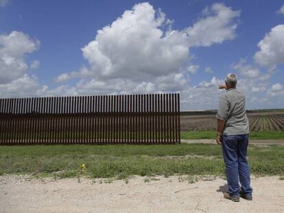 Un hombre señala un tramo de la valla fronteriza incompleta en Brownsville (Texas)