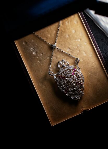 Colgante Belle Époque de diseño floral con lazada, realizado en platino, rubíes y diamantes tallados a medida. En la base reproduce el trébol anagrama de la firma desde 1842.