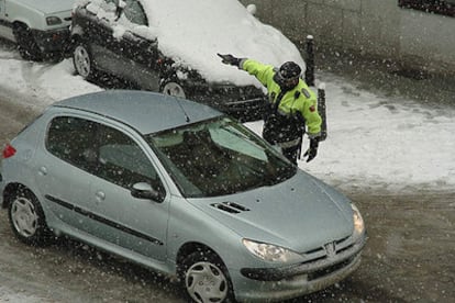 Un policía indica a un conductor en Segovia la obligatoriedad de usar cadenas.