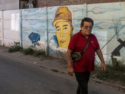 Un adulto camina por un pasaje junto a un mural de un delincuente fallecido en la comuna de Padre Hurtado.