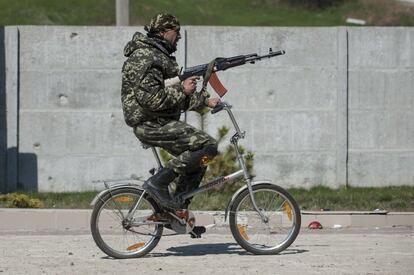 Un militar ucranio monta en bici con un arma por las calles de Shyrokyne, al este de Ucrania.
