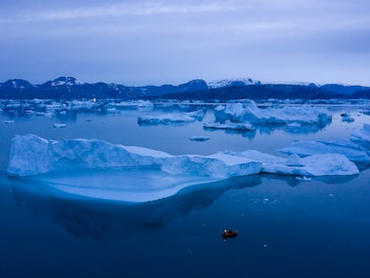 A boat navigates at night next to large icebergs near the town of Kulusuk, in eastern Greenland on Aug. 15, 2019.