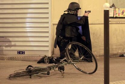 Un policia, de genolls, es cobreix pel pas d'un vehicle sospitós en un dels llocs atacats divendres.