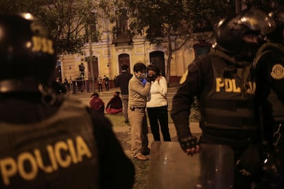 Um casal escuta as notícias na noite eleitoral em uma rua de Lima, neste domingo.