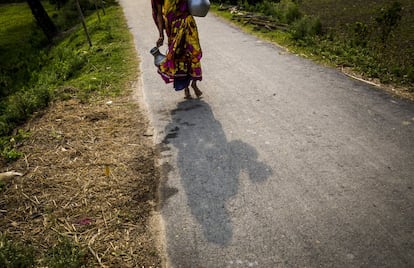 Una mujer lleva a su casa el agua que ha cogido de un pozo entubado del lugar en una zona rural de Bangladesh.