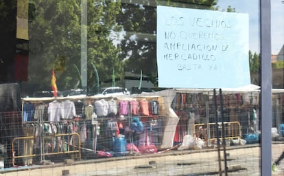 Vecinos y comerciantes han colgado carteles con mensajes de protesta contra la ampliación del mercadillo a la calle de Santa Catalina, cuyas obras se ven en el reflejo de la ventana.