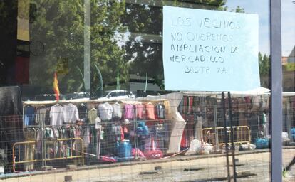 Vecinos y comerciantes han colgado carteles con mensajes de protesta contra la ampliación del mercadillo a la calle de Santa Catalina, cuyas obras se ven en el reflejo de la ventana.