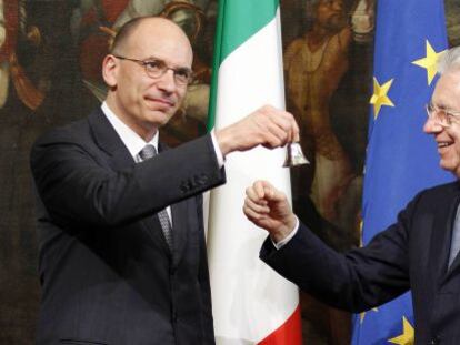 Enrico Letta (izq.), hace sonar una campanilla de plata en señal del inicio de su mandato, junto al jefe del goibierno saliente, Mario Monti.
