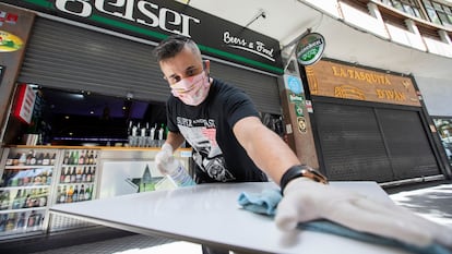 Un empleado de una cafetería limpia una mesa en Las Palmas de Gran Canaria.